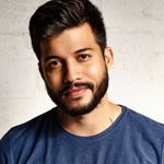 Close-up portrait of a handsome man with a beard in casual attire, smiling warmly.